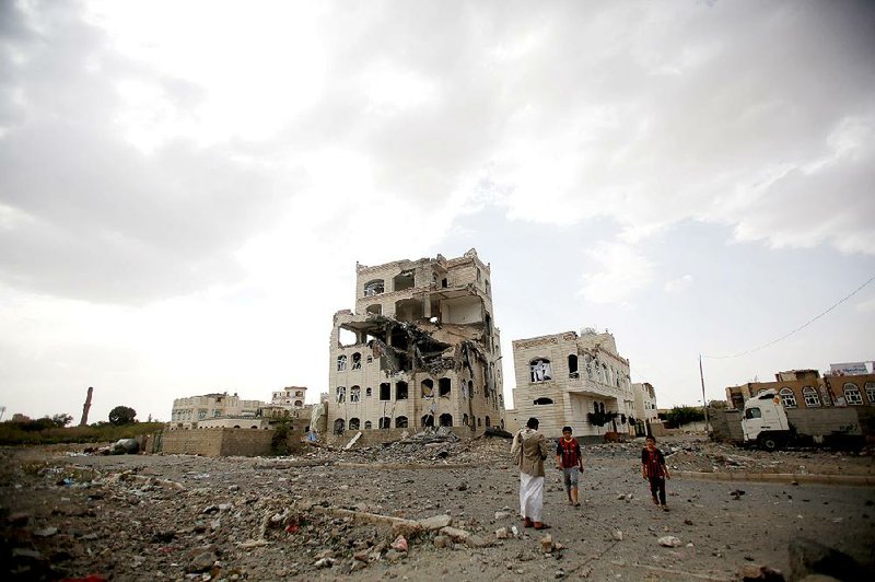 People on Monday stand by a building destroyed by a Saudi-led airstrike in Sanaa, Yemen.