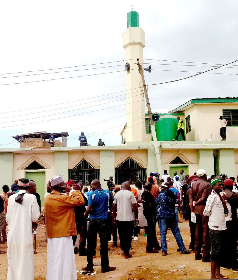 People gather Monday near a mosque where a bomb exploded Sunday in Jos, Nigeria.