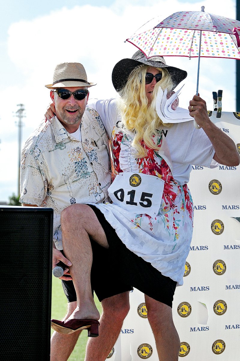 Jeff Culhane, with team Not So Happy Feet, tries to jump into the arms of master of ceremonies Barry Cobbs during the “Walk Off” event at the Northwest Arkansas Women’s Shelter’s Champions in Heels fundraiser in 2014. Men in high heels, including teams from local police departments and businesses, will compete in individual and 4x100m relay races July 18 to raise awareness about domestic violence and sexual assault.