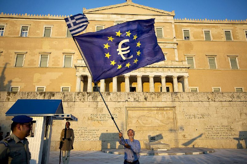 A demonstrator in front of the Greek Parliament building waves a European Union flag bearing a euro symbol Thursday in Athens.