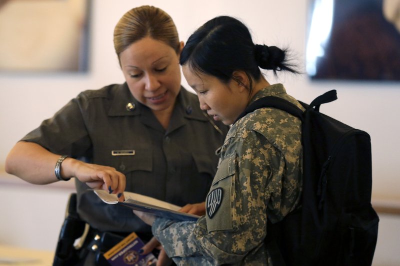 In this photo taken, June 30, 2015, New York State Trooper Maxine Mendez, left, speaks to Xiaojiao Zuo, of Queens, about employment opportunities during a U.S. Chamber of Commerce Foundation Hiring Our Heroes jobs expo at Citi Field in New York. The Labor Department releases weekly jobless claims data on Thursday, July 9, 2015. 