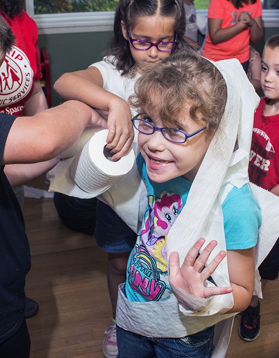 Jayla Echra, 6, gets covered in toilet paper as she is transformed into a mummy during the Magic of Flight camp sponsored by Friendship Community Care of Russellville in partnership with Kids Place day care. The camp, held last week, is part of Friendship Community Care’s new program, Link It Up!, which will also provide after-school care during the year for special-needs school-age children and their siblings. The after-school program will be held at Friendship Community Care’s preschool facility on Russell Road.