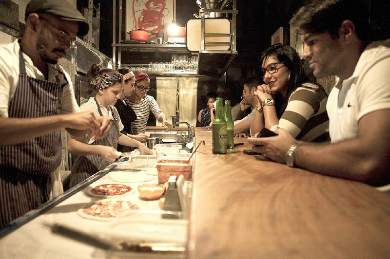Customers enjoy drinks and watch pizzas being made at the bar of Ferro & Farinha in Rio de Janeiro in early July. The restaurant’s owner, Sei Shiroma, 29, opened the eatery after his mobile kitchen proved popular.