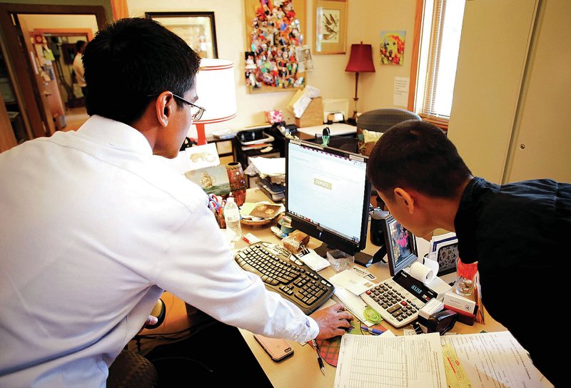 Nauman Malik (left) and Kyle Jiang, both juniors at Fayetteville High School, review the website Friday they developed for the Fayetteville Senior Activity and Wellness Center at the center. The two students won the NWA Tech Council’s Biz Ed Conference challenge for finding a solution for a small business problem and began an internship with HumanLink in Fayetteville.