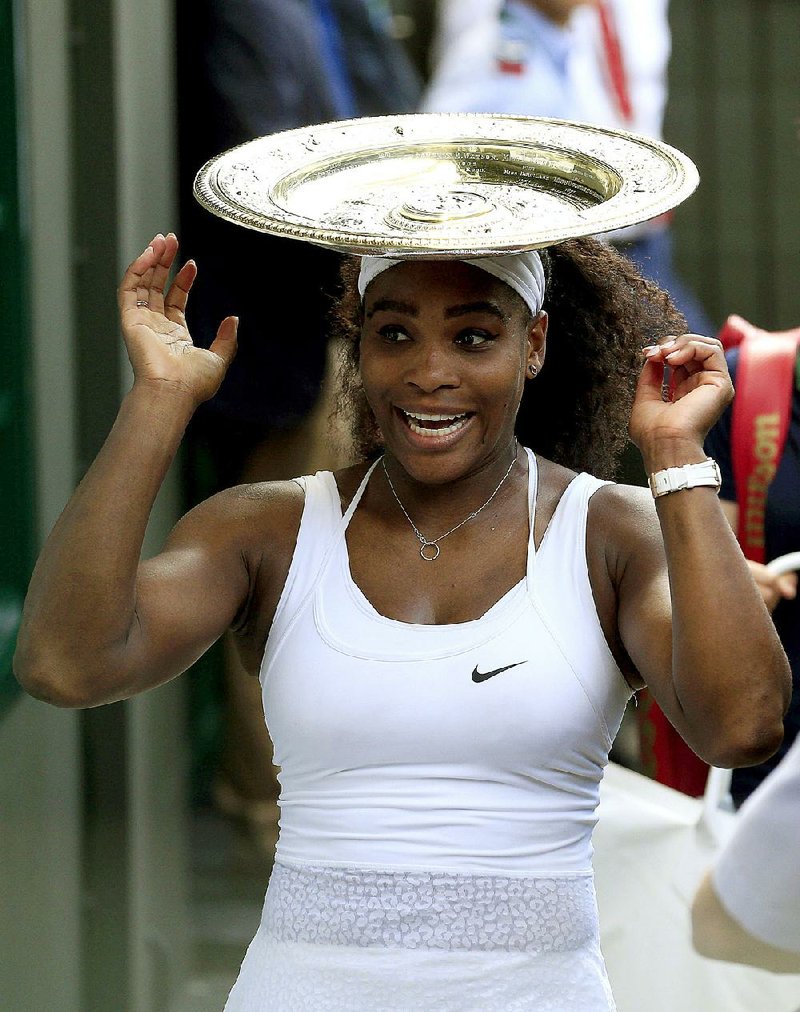 Serena Williams does a balancing act with her championship trophy after her 6-4, 6-4 victory over Garbine Muguruza on Saturday at Wimbledon. It was Williams’ fourth consecutive Grand Slam victory.