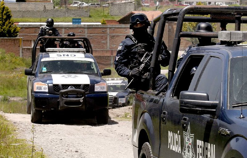 Federal police stand guard Monday by a half-built house near the maximum security prison in Almoloya, Mexico. A manhunt that included highway checkpoints, stepped-up border security and closure of an international airport failed to turn up any trace of Mexican drug kingpin Joaquin “El Chapo” Guzman.