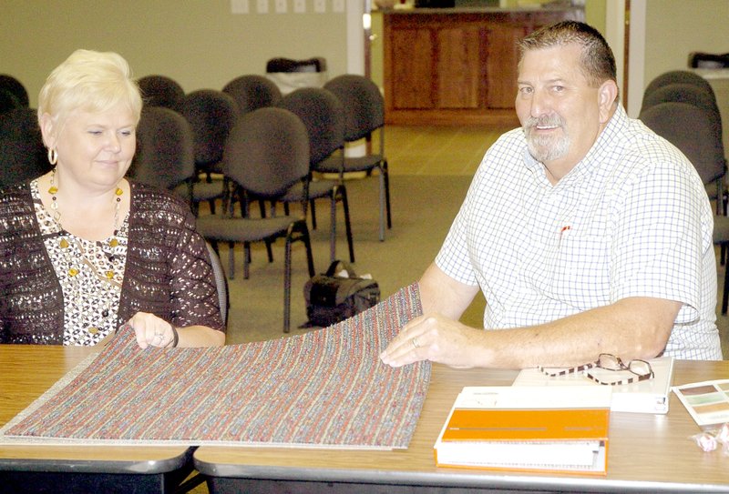 PHOTO BY RICK PECK Ann Miller, Nabholz Construction, and Bob Campbell, McDonald County School District, look at a sample of carpet being considered as an option to cover a crack in a concrete floor at the entrance of the new Pineville safe room/gymnasium.
