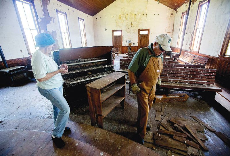 Nola Moser and her husband, Jeff, walk inside Mount Hebron M.E. Church on Thursday in Rogers. According to Moser, vandals have broken out several windows recently in the church, which was built in 1904.