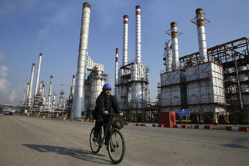 An Iranian oil worker rides a bicycle to get around an oil refinery near Tehran in December. Oil prices that slumped last year could take another hit if Iran begins to pump more crude into the market. 