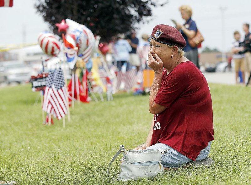 Laurie Norman kneels Friday at a makeshift memorial outside a military recruiting center in Chattanooga where a gunman who killed four Marines at another nearby facility opened fire Thursday. 