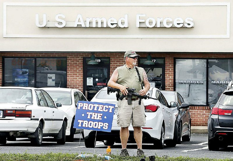 A man who said he was there “to protect the troops”  brandishes a rifle outside a recruiting center Friday in Winchester, Va. 