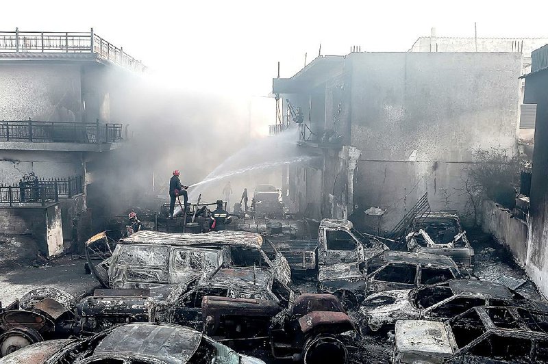Firefighters spray burned-out cars and surrounding houses Friday in Neapoli in southern Greece. 