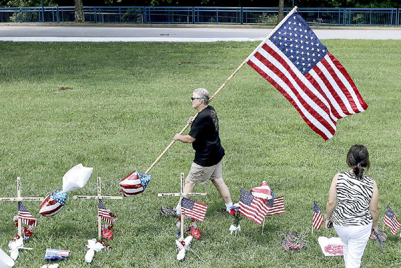 Mark Fuller and his wife, Donna, place an American flag at a makeshift memorial Saturday on Amnicola Highway in Chattanooga, Tenn., for the victims of Thursday’s shootings. Fuller said his daughter-inlaw is a Navy reservist and a Chattanooga police officer. 