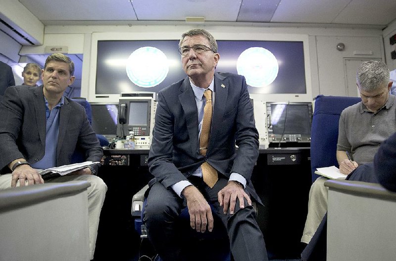 U.S. Defense Secretary Ashton Carter (center) and U.S. Department of Defense press secretary Peter Cook (left) listen to a question during a news conference aboard a military aircraft en route to Israel on Sunday.