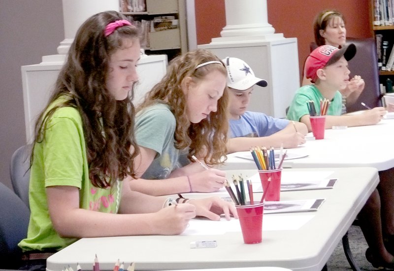 Lynn Atkins/The Weekly Vista Sisters Julia and Hadassha Holden, along with Elijah Patterson and Elisha Holden, concentrate on drawing a face at the Bella Vista Library during Homeschoolers Corner, a monthly program.