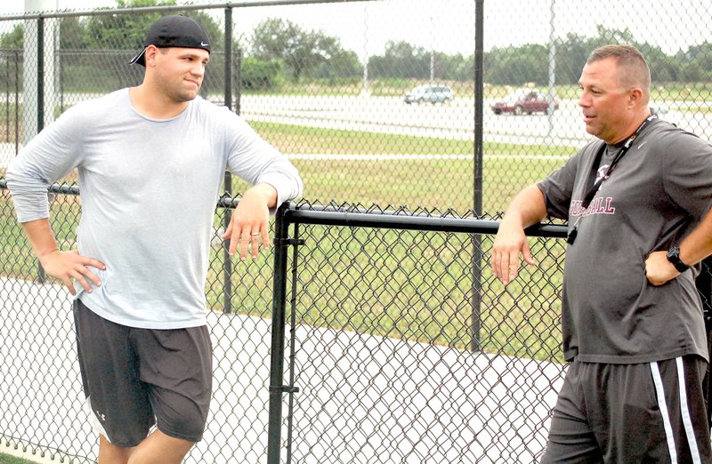 Graham Thomas/Herald-Leader Former Arkansas and NFL standout Peyton Hillis, left, visits with Siloam Springs head football coach Bryan Ross during a weather delay in 7-on-7 action Monday at Panther Stadium in Siloam Springs. Hillis plans on volunteer coaching this fall for the Panthers.