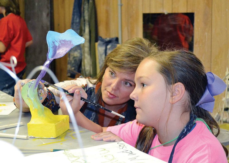 Amy Tarpley, executive director of the Arkansas River Valley Arts Center in Russellville, left, offers a little hands-on assistance to Madison Pennington, one of the participants in the center’s recent summer art camp. Pennington and her fellow campers used various materials to create abstract organic sculptures.