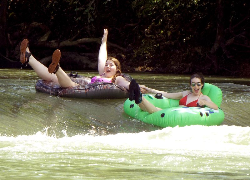 Tierney and Morgan Herbert ride tubes over a set of rapids at the Siloam Springs Kayak Park on Thursday afternoon.