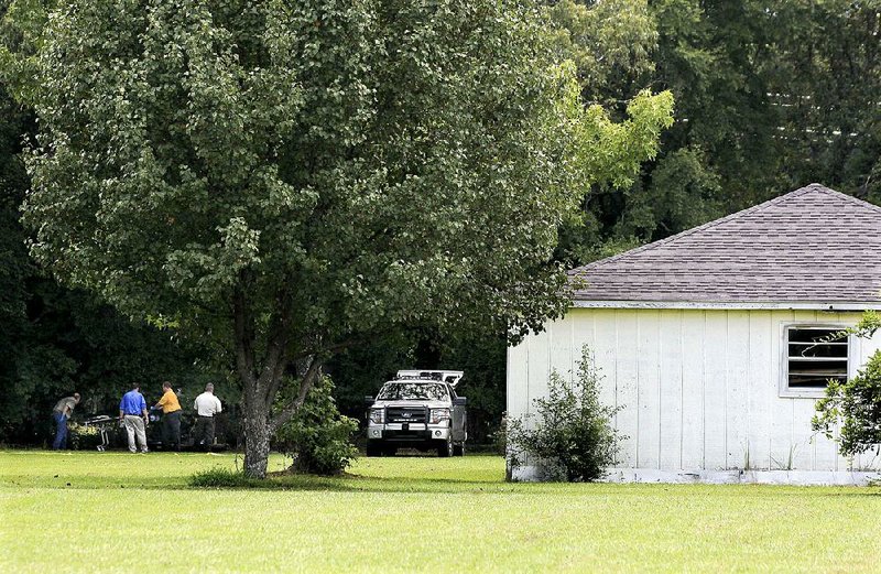 The Faulkner County coroner and Conway police remove the bodies of a couple found shot to death Wednesday in a wooded area behind their Quail Run Circle home in Conway.