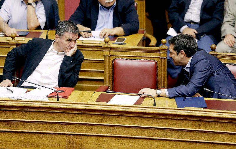 Greece’s Prime Minister Alexis Tsipras (right) chats with Finance Minister Euclid Tsakalotos during an emergency parliament session Wednesday in Athens. 