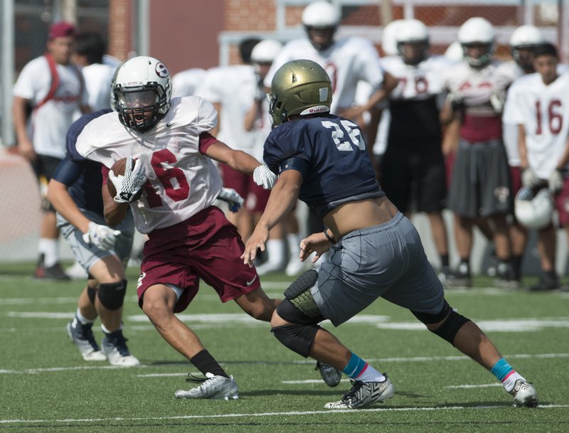 Kyler Williams of Springdale High tries to get around a Shiloh Christian defender Monday at a summer team football camp at Jarrell Williams Bulldog Stadium in Springdale.