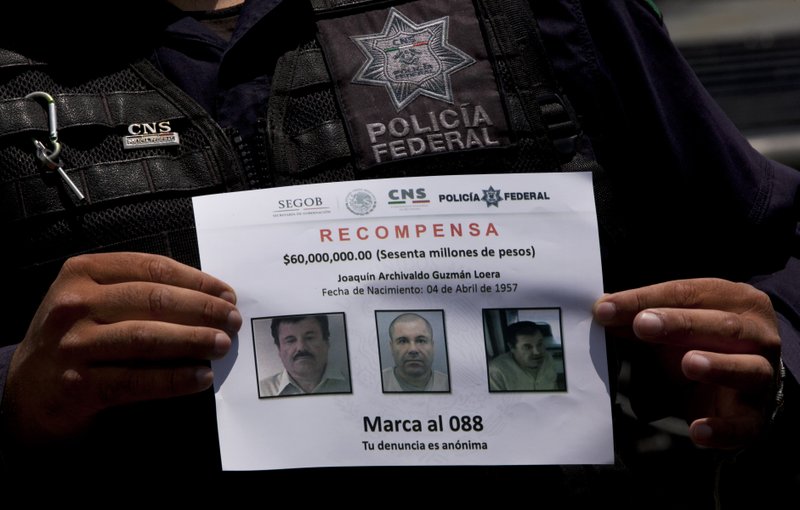In this July 16, 2015 file photo, a Federal Police shows a reward notice for information leading to the capture of drug lord Joaquin "El Chapo" Guzman, who made his escape from the Altiplano maximum security prison via an underground tunnel,  in Almoloya, west of Mexico City.