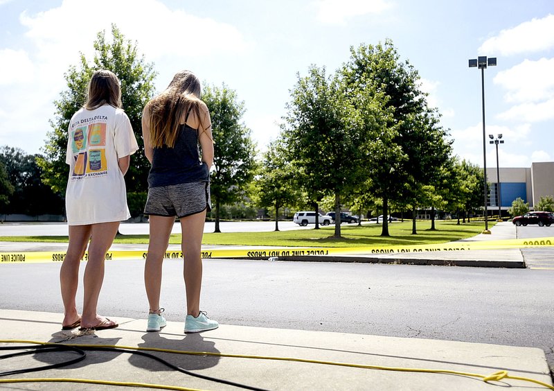 Two women stand in silence Friday outside the Grand Theatre in Lafayette, La., where a gunman opened fire Thursday night. 