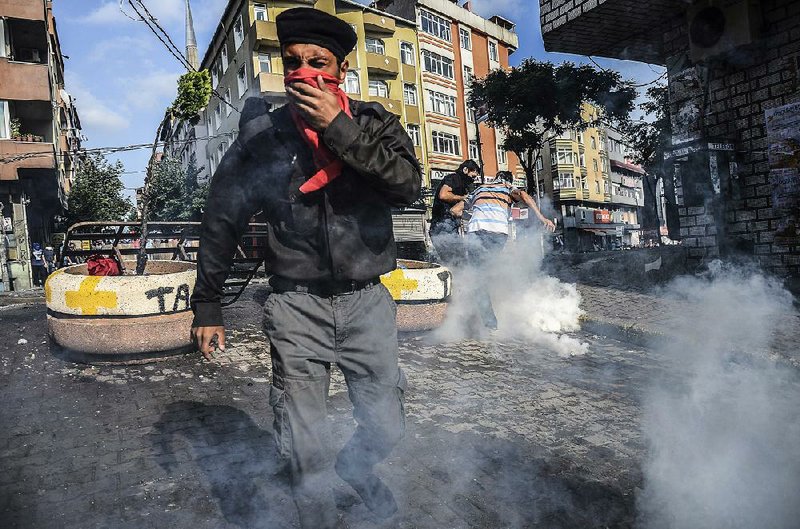 Protesters in Istanbul dodge tear gas fired Saturday by police during a demonstration over Monday’s Islamic State suicide bombing in Suruc in southeastern Turkey that killed 32 people, mostly Kurds. 