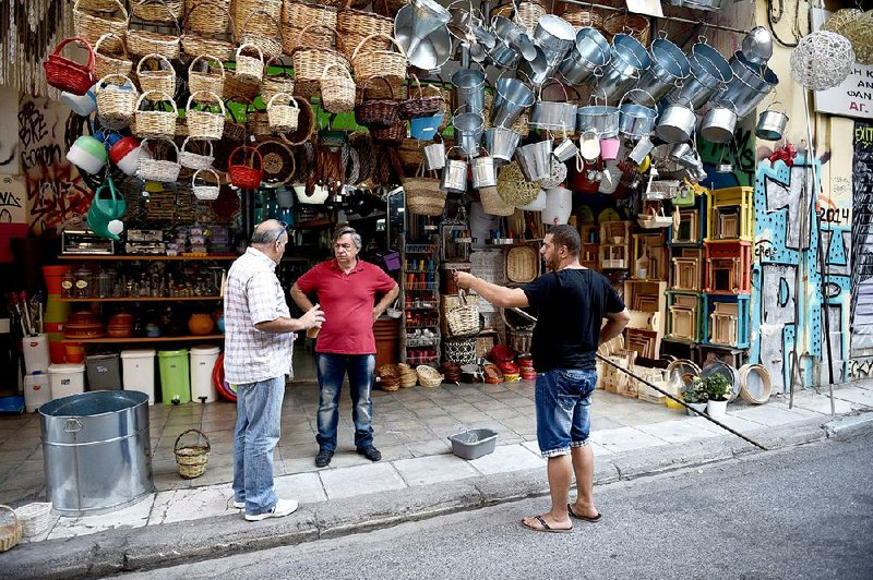 People chat outside a shop in Athens, Greece, on Saturday. Lenders in Greece reopened with limited services last week.