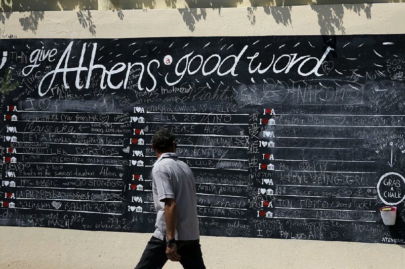 A pedestrian looks at a board where people can write their comments about Athens, the Greek capital, on Monday.