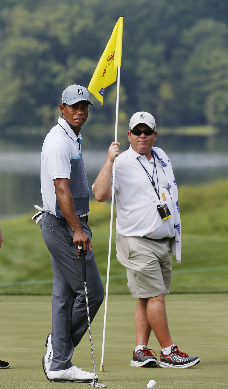 Tiger Woods,left, watches a putt on the 16th green during a practice round for the Quicken Loans National Golf tournament at the Robert Trent Jones Golf Club in Gainesville, Va., Tuesday, July 28, 2015. 