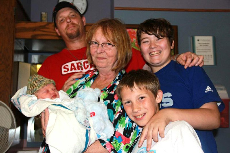 In a photo taken before she received her diagnosis of leukemia, Melanie Joann Clark, center, holds her grandson Aiden. Also shown are her son, Timothy, from left, and grandsons Austin and T.J.