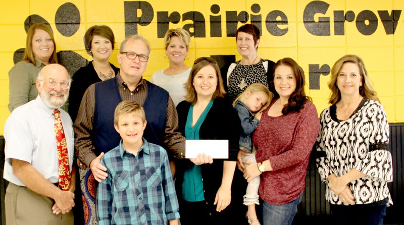 LYNN KUTTER ENTERPRISE-LEADER Geron Vail, of Fayetteville, (holding the check) donated $5,000 to Prairie Grove Elementary School to purchase books so that at-risk students can start their own home library next fall. Along with Vail are his daughters Terah Vail and Andrea Wilson and grandchildren Allie and Caleb Wilson. Caleb is a second-grader in Prairie Grove. Representing the school on the back row Suzanne Ezell, Kristin Taylor, Kim Pinkley and Holly Madar. Ralph Nesson with Bright Futures stands front left, and Carmel Perry, director of the district&#8217;s Coordinated School Health program, stands front right.