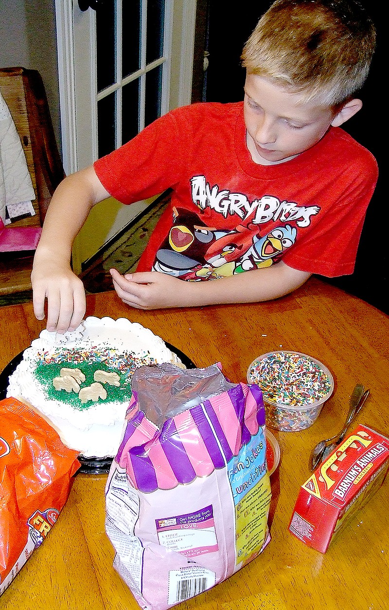 Tom A. Throne/The Weekly Vista Cole Steinlage decorates a cake using animal crackers, both plain and frosted.