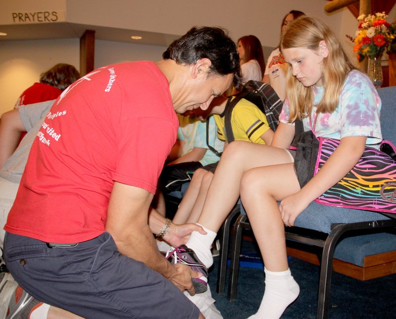 LYNN KUTTER ENTERPRISE-LEADER Jeff Silva with Farmington United Methodist Church helps this young girl try on a pair of new tennis shoes at the Farmington Back to School Bonanza last year. The church is expecting to serve 550-600 children at its 10th Bonanza on Thursday, Aug. 6.