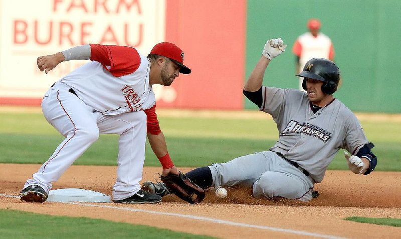 Arkansas third baseman Brian Hernandez bobbles the ball as Northwest Arkansas left fielder Lane Adams (right) slides safely into third base during the Travelers’ 12-9 victory over the Naturals on Wednesday at Dickey-Stephens Park in North Little Rock.