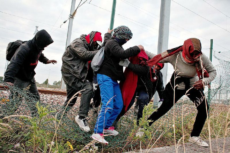 Foreigners flee railway police through a fence Wednesday near their squalid camp in Calais in northern France. About 3,000 foreigners have been living around Calais as they attempt to get to England.