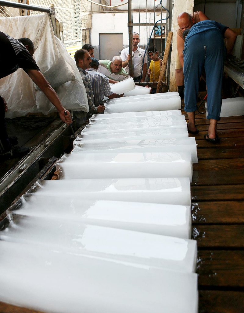 People buy blocks of ice Thursday in Baghdad as the Middle East deals with a summer heat wave. 