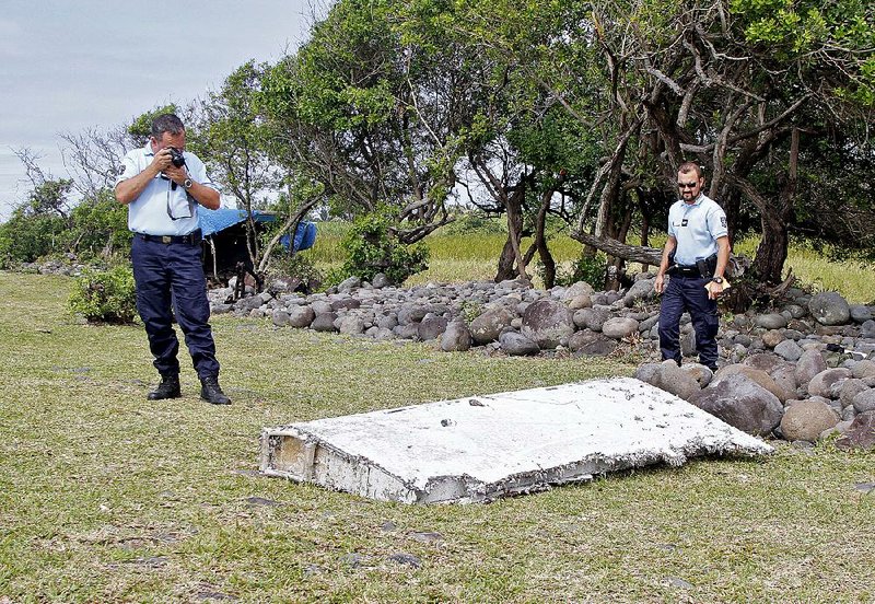 French police officers examine a piece of an airplane wing found Wednesday on Reunion Island in the Indian Ocean. 