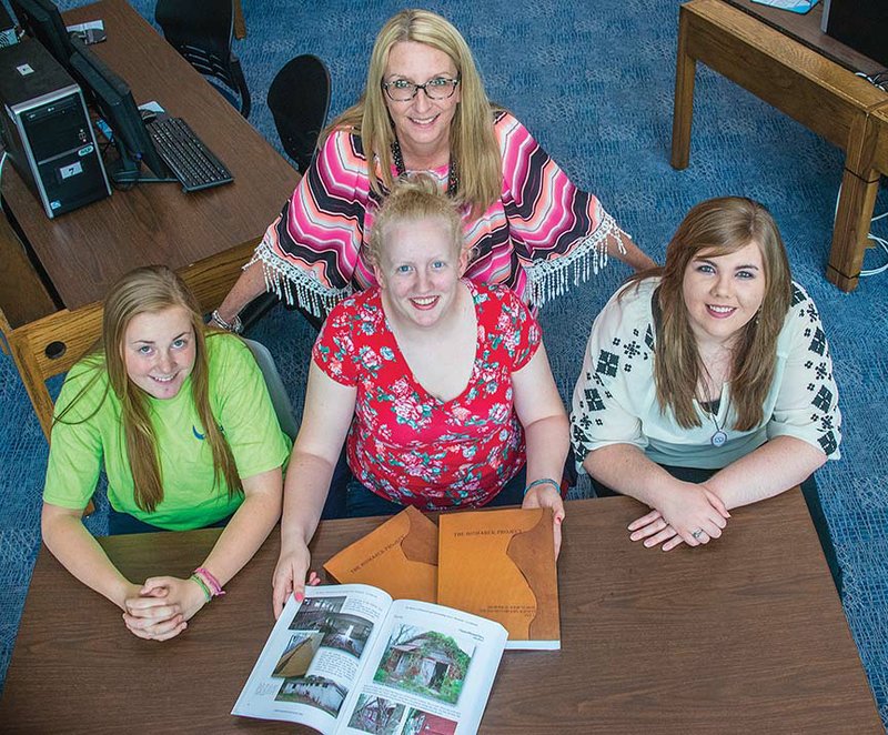 Morgan Cooper, sitting, from left, Taylor Rynders and Sarah Smith show copies of The Bismarck Project, which they helped compile. The book is on the history of Bismarck and surrounding areas. Standing with the students is Cindy Bubulka, Bismarck High School librarian.