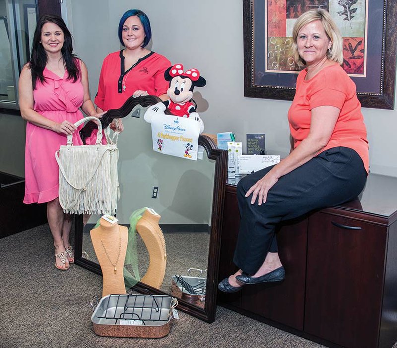 Lorie Yates-Dodson, from left, Taylor Watts and Annette Miller pose with some of the many auction items that will be available during The Great Escape, scheduled for 9 a.m. to 3 p.m. Aug. 29 at the Conway Expo Center. Tickets are $5 for the event, which includes spa services for $10 each, shopping and a style show. Proceeds will go to the Women’s Shelter of Central Arkansas, which is celebrating its 20th year in Conway.