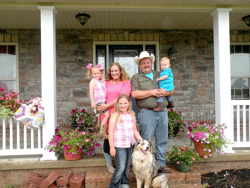 The Lance Humphries family of Ash Flat is the 2015 Sharp County Farm Family of the Year. Lance and his wife, Mandy, hold their two younger children, Graci, 4, and Harris, 1, while their oldest daughter, Taci, 8, pets Gus, the family’s Australian shepherd.