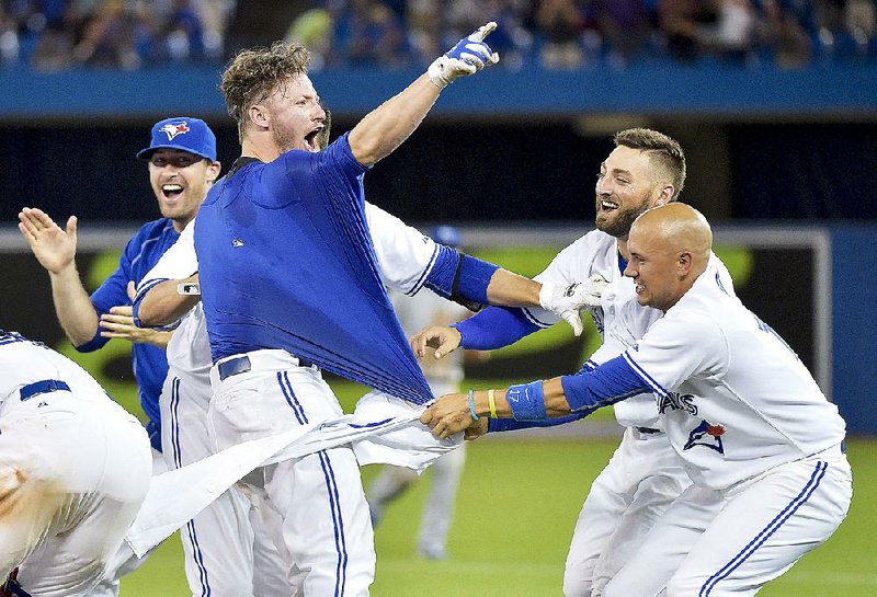 Toronto third baseman Josh Donaldson (left) has his jersey ripped off by teammates after his RBI single in the bottom of the 11th inning gave the Blue Jays a 7-6 victory over Kansas City on Friday.