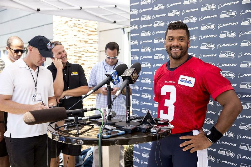 Seattle Seahawks quarterback Russell Wilson, right, smiles during a news conference after NFL football training camp on Friday, July 31, 2015, in Renton, Wash. 