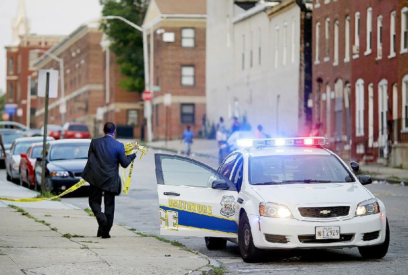 A Baltimore police official removes crime-scene tape from a corner where a shooting victim was discovered Thursday. 