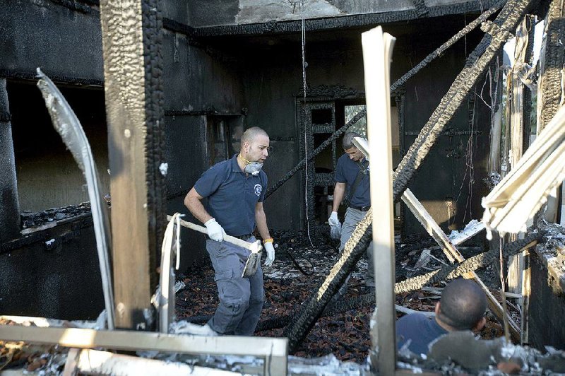 Israeli policemen inspect a Palestinian home that was set afire Friday in Duma near the West Bank city of Nablus. 