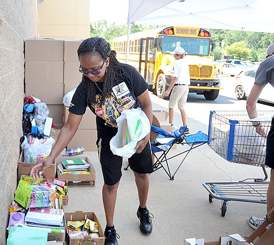 The Sentinel-Record/Mara Kuhn SORTING SUPPLIES: Sandra Peppers, a United Way of Garland County volunteer and employee of Hot Springs High School, sorts donated school supplies Friday at Wal-Mart on Central Avenue during the United Way Stuff the Bus event.