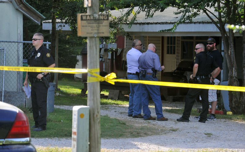 Springdale police officers wait Friday outside a home on the corner of Gibbs Road and Nichols Road in Springdale as they investigate a shooting.