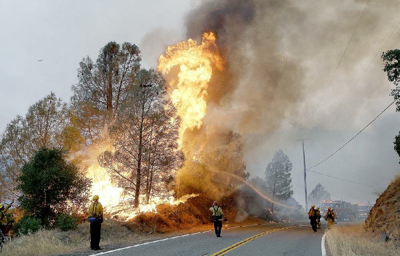 Firefighters respond to a fire Friday along Morgan Valley Road near Lower Lake, Calif. Gov. Jerry Brown declared a state of emergency as wildfires burn in woodlands across California.