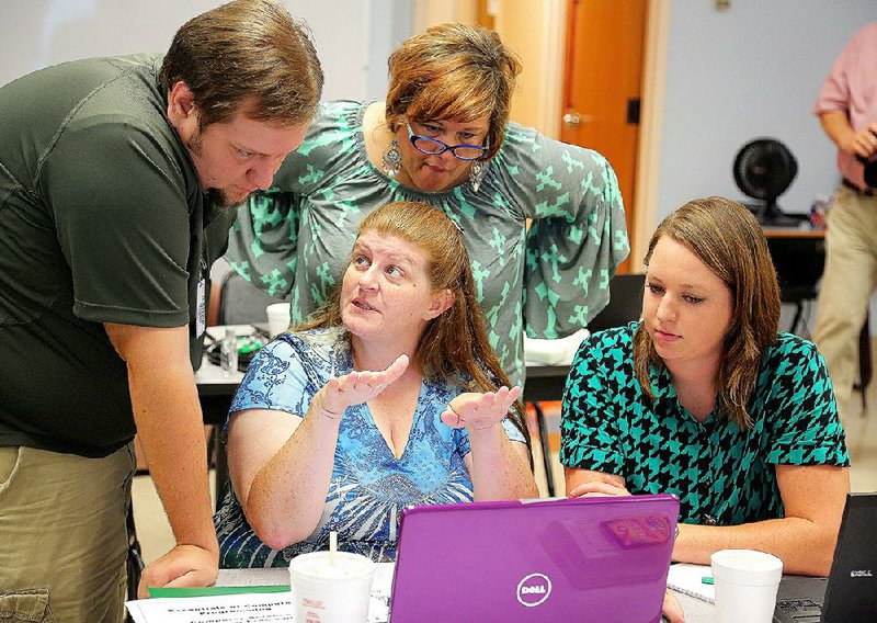 High school teachers Daniel Traylor of Valley Springs (from left), Cassandra Loskot of Flippin, Gerri McCann (standing) of Manila and Lauren Taylor of Dardanelle work to solve a problem Wednesday during computer coding training camp at the Arkansas School for Mathematics, Sciences and the Arts. 